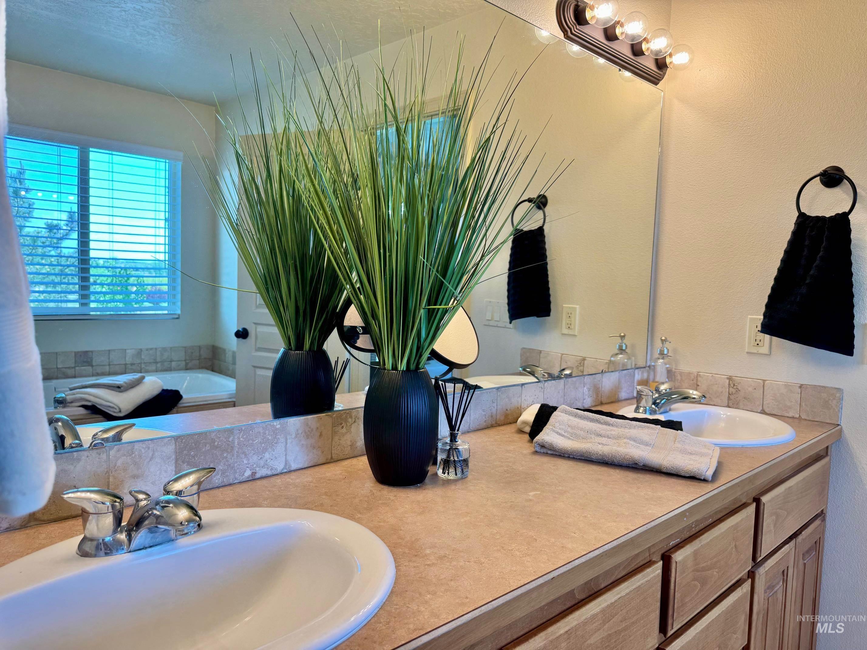 9299 Kemp Road Middleton, ID 83644 - Photo 26 of 50 Double vanity with integrated sinks, a large mirror, and a multi-bulb vanity light fixture