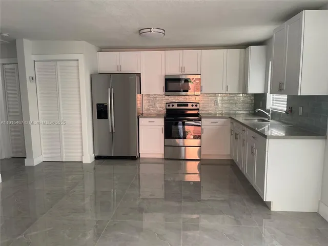 a kitchen with stainless steel appliances granite countertop a refrigerator and a stove top oven
