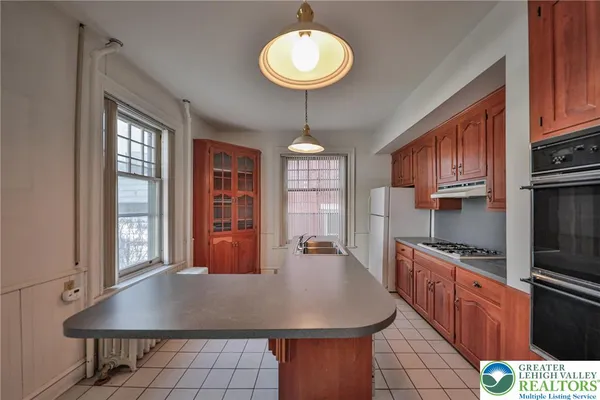 a kitchen with stainless steel appliances granite countertop a stove a refrigerator a sink a dining table and chairs with wooden floor