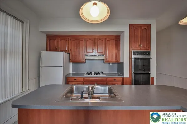 a kitchen with kitchen island granite countertop a refrigerator a stove and a sink with wooden floor