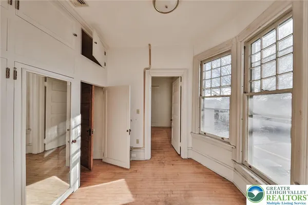 a view of empty room with wooden floor and fan