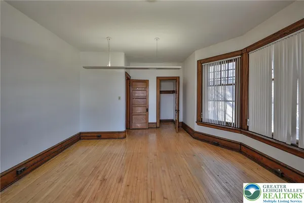 a view of empty room with wooden floor and fan
