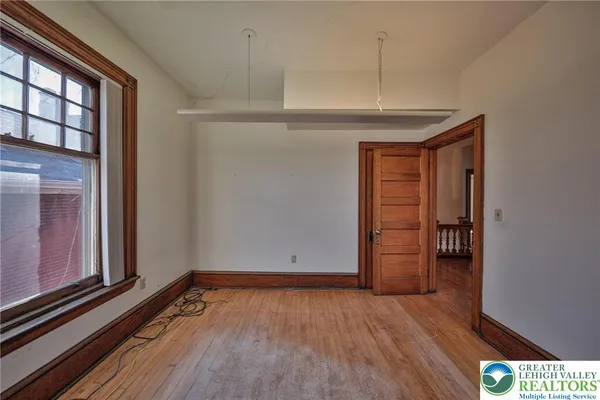 a view of an empty room with wooden floor and a window