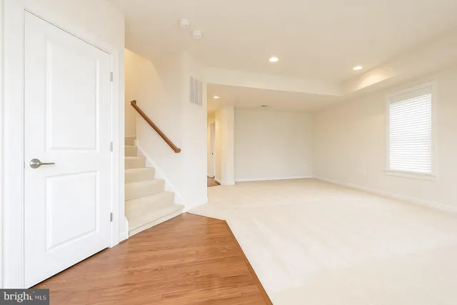 a view of an empty room with wooden floor and stairs