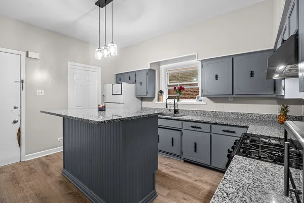 a kitchen with granite countertop a sink a counter top space and cabinets