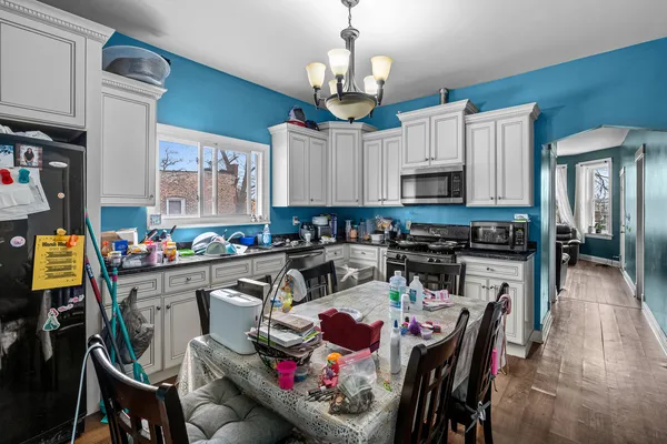 a kitchen with stainless steel appliances granite countertop a stove top oven a refrigerator a dining table and chairs with wooden floor