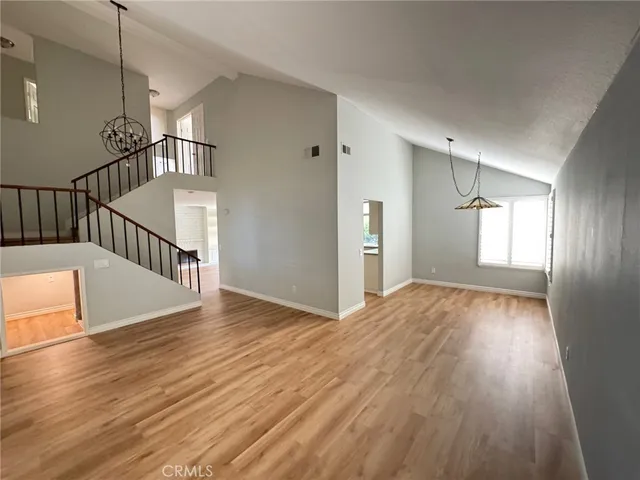a view of an empty room with wooden floor and fan