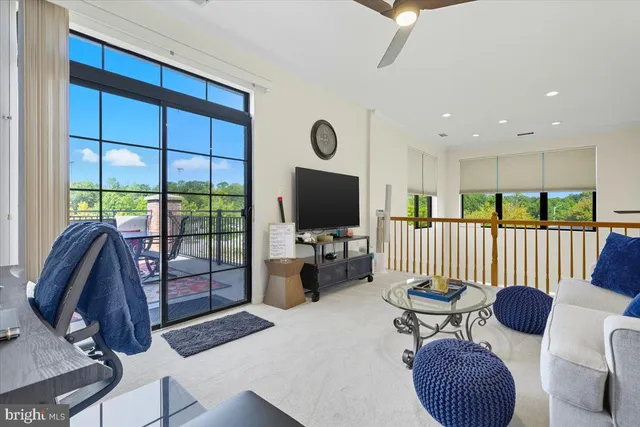 a living room with furniture a flat screen tv and floor to ceiling window