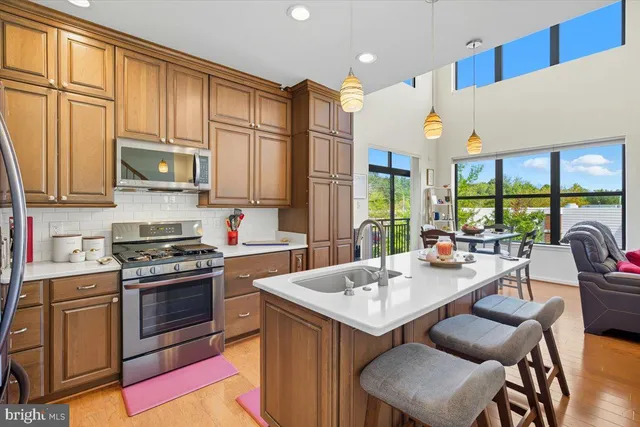 a kitchen with stainless steel appliances granite countertop a stove a sink dishwasher and a refrigerator with wooden cabinets