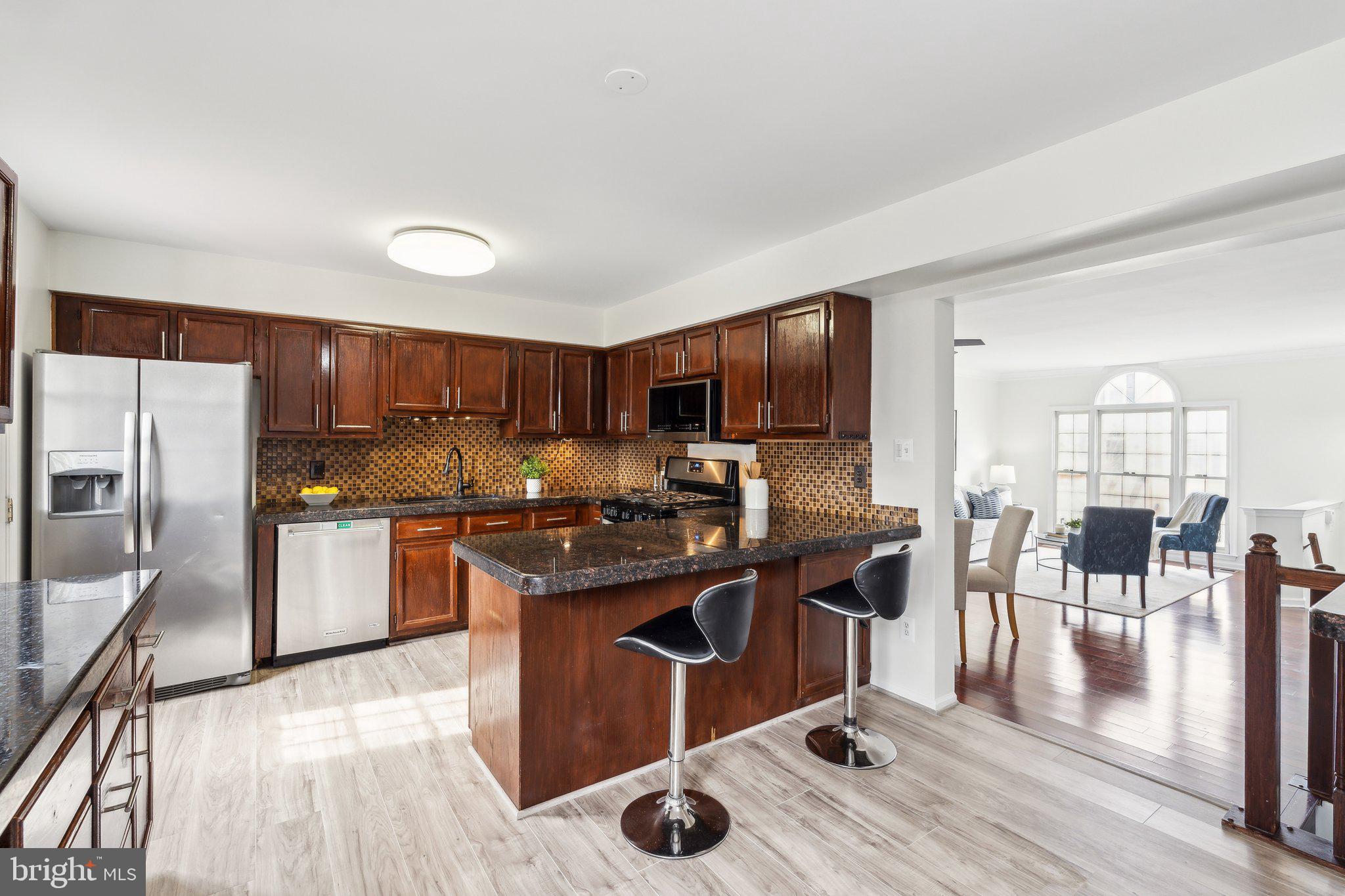 46924 Rabbitrun Terrace Sterling, VA 20164 - Photo 12 of 38 a kitchen with stainless steel appliances granite countertop a stove top oven a sink dishwasher a dining table and chairs with wooden floor