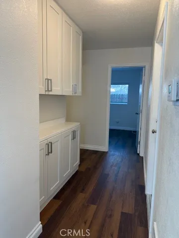 a view of a utility room with wooden floor and cabinets