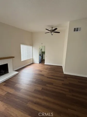 an empty room with wooden floor chandelier fan and windows