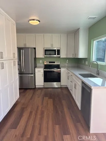 a kitchen with granite countertop a refrigerator stove top oven and sink