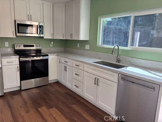 a kitchen with stainless steel appliances granite countertop a sink a stove a microwave and wooden cabinets