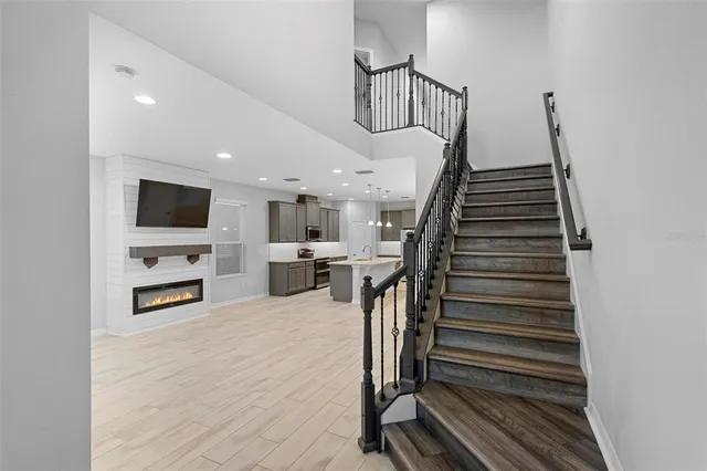 a view of a livingroom with a flat screen tv staircase and a kitchen view