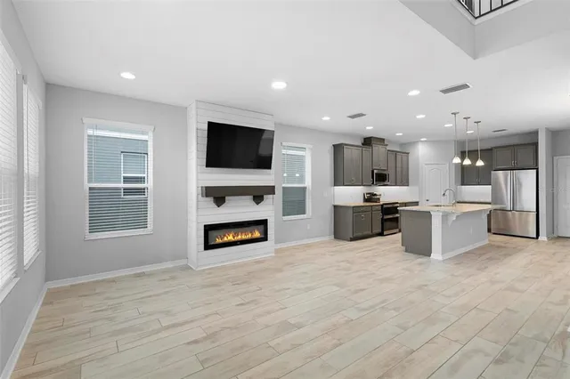 a living room with stainless steel appliances furniture and a kitchen view