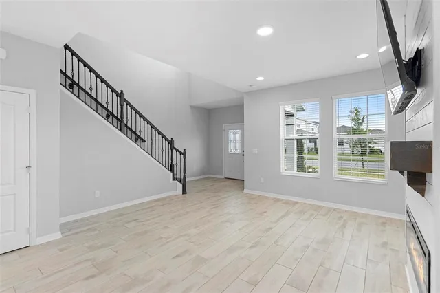 a view of an empty room with a window and wooden floor