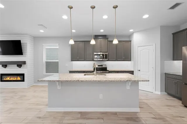 a large kitchen with granite countertop a large counter top stainless steel appliances and cabinets