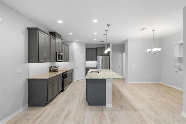 a large kitchen with stainless steel appliances kitchen island a large counter top a sink a stove and a refrigerator