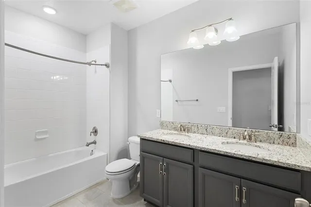 a bathroom with a granite countertop sink toilet a large mirror a bathtub and shower