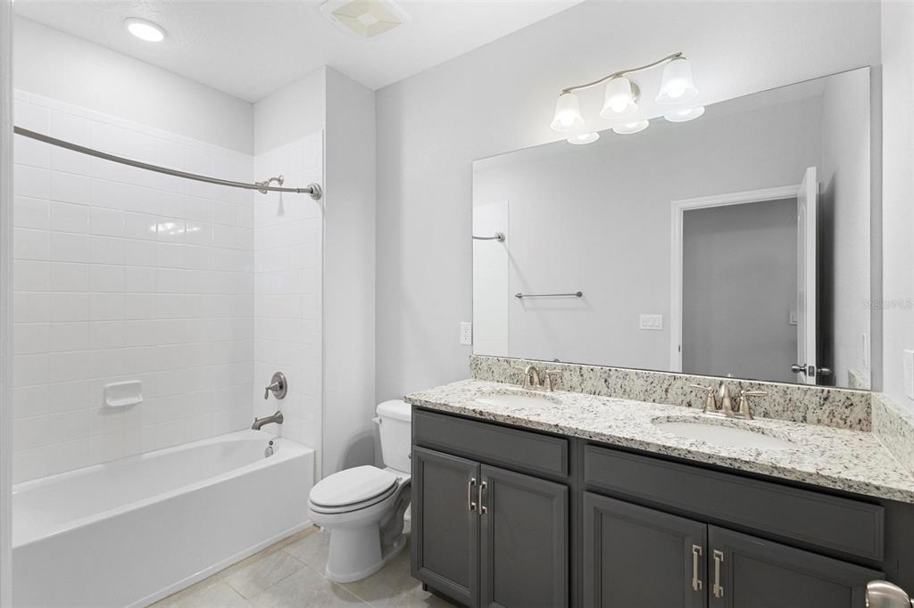 730 Rivington Drive DeBary, FL 32713 - Photo 31 of 47 a bathroom with a granite countertop sink toilet a large mirror a bathtub and shower
