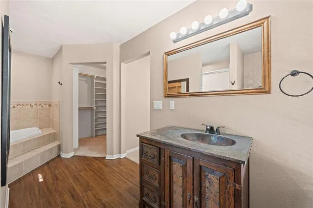 a bathroom with a sink vanity granite tub and a mirror