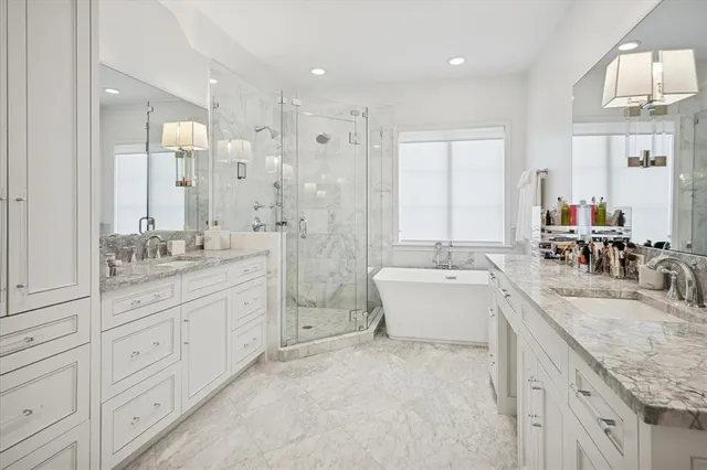 a bathroom with a granite countertop double vanity sink large mirror and a bathtub
