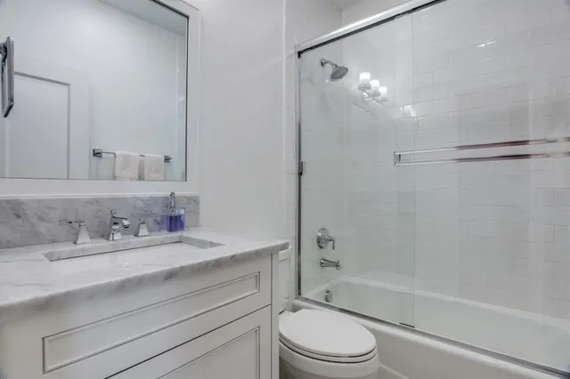 a bathroom with a granite countertop sink a toilet and shower