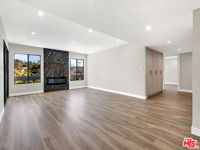 a view of an empty room with closet and wooden floor