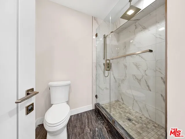 a bathroom with a granite countertop shower a toilet and a sink