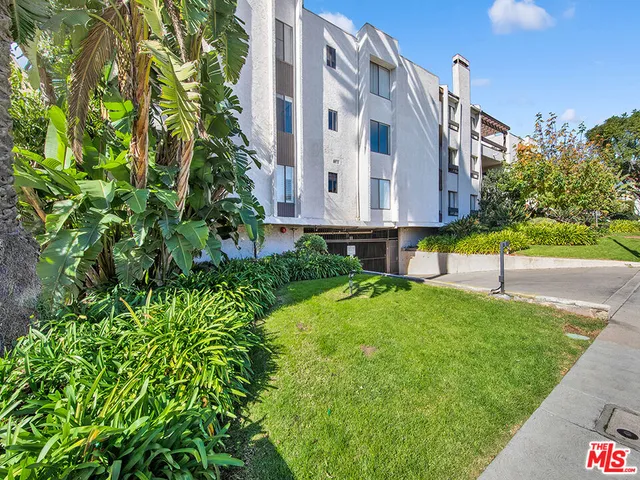 a view of a tall building with a yard and sitting area