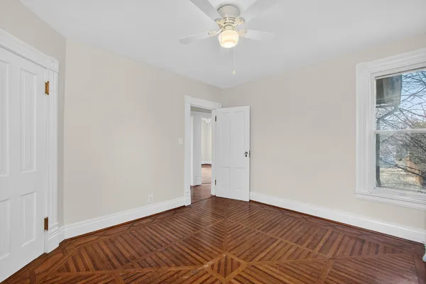 a view of an empty room with wooden floor and a window