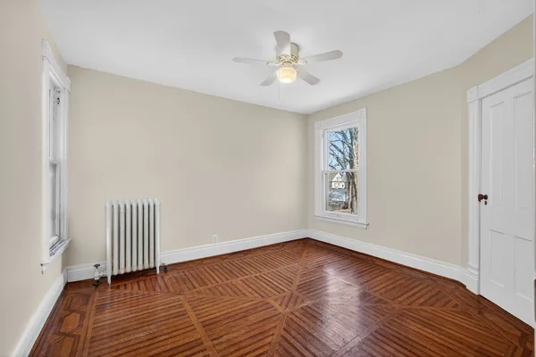 an empty room with wooden floor and a ceiling fan
