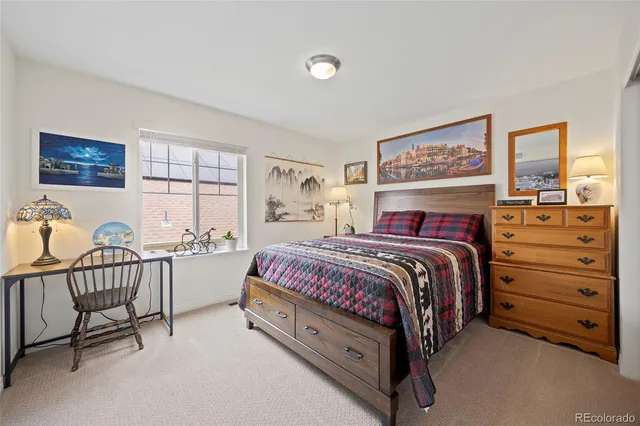 a bedroom with a bed a chair and next to a window