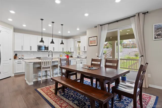 a dining room with stainless steel appliances granite countertop a table chairs and a living room view