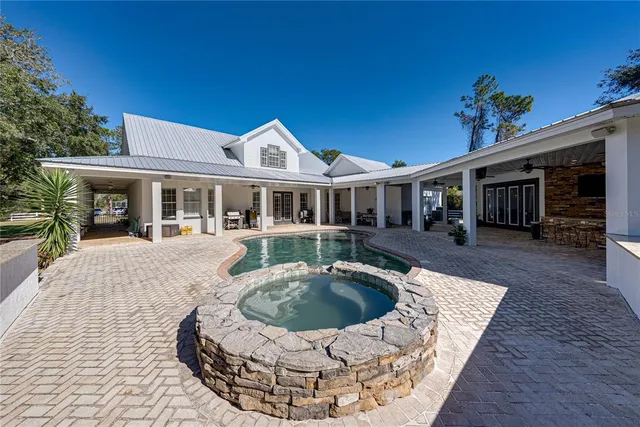 a view of a house with backyard swimming pool and sitting area
