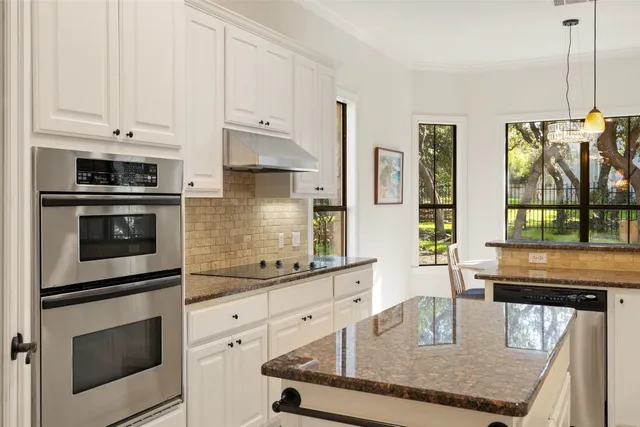 a kitchen with stainless steel appliances granite countertop a stove a sink and white cabinets