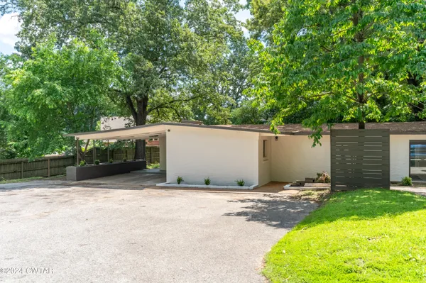 a backyard of a house with large trees and plants