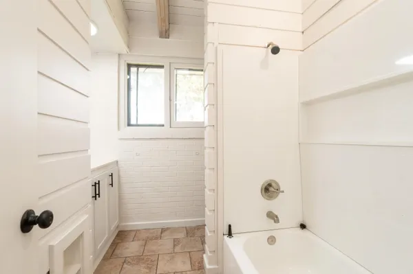 a bathroom with a tub a sink a window and a shower