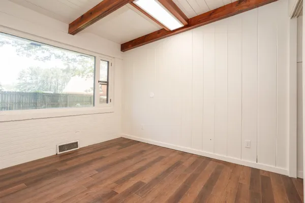 a view of empty room with wooden floor and fan