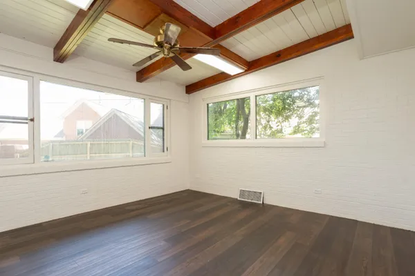 an empty room with wooden floor chandelier and windows