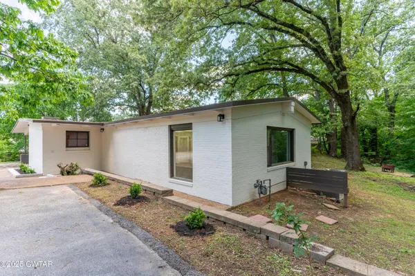 a front view of house with yard and trees in the background