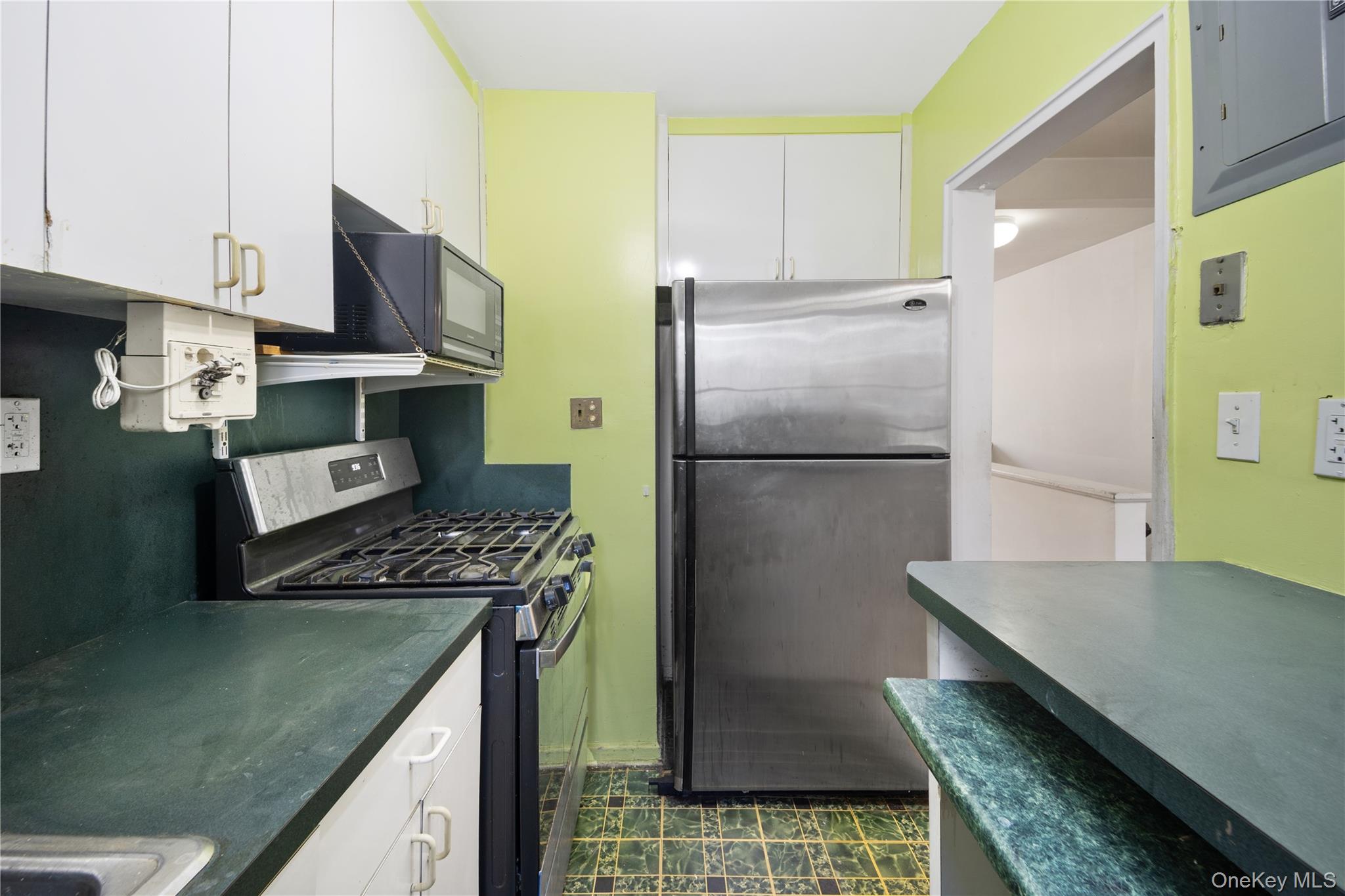 226-29 Manor Road, Unit UPPR Queens, NY 11427 - Photo 9 of 21 Kitchen featuring appliances with stainless steel finishes, white cabinets, electric panel, and dark countertops