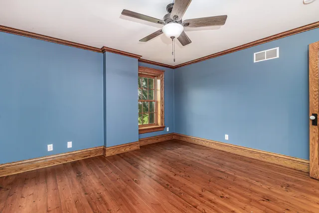 a view of an empty room with window and wooden floor