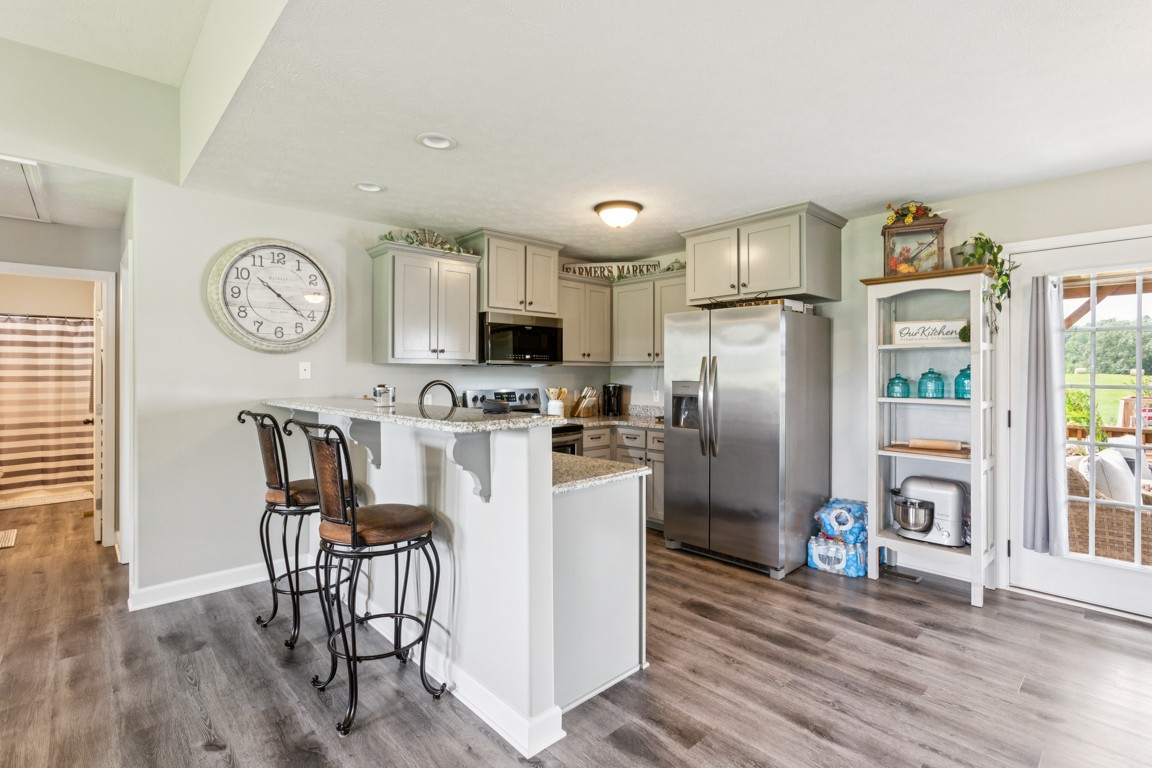 4510 Long Creek Road Lafayette, TN 37083 - Photo 7 of 25 a kitchen with stainless steel appliances granite countertop a refrigerator a stove a sink and a dining table with wooden floor