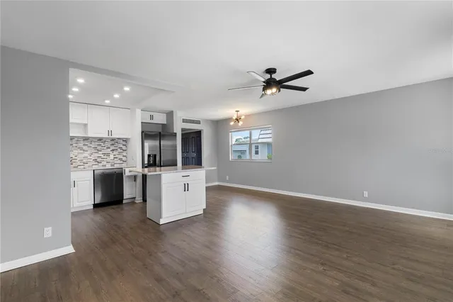 a view of an empty room with kitchen and stove top oven
