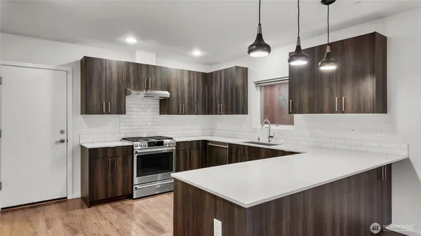 a kitchen that has a sink a stove and a microwave oven with wooden floor