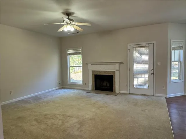 an empty room with chandelier fan and windows
