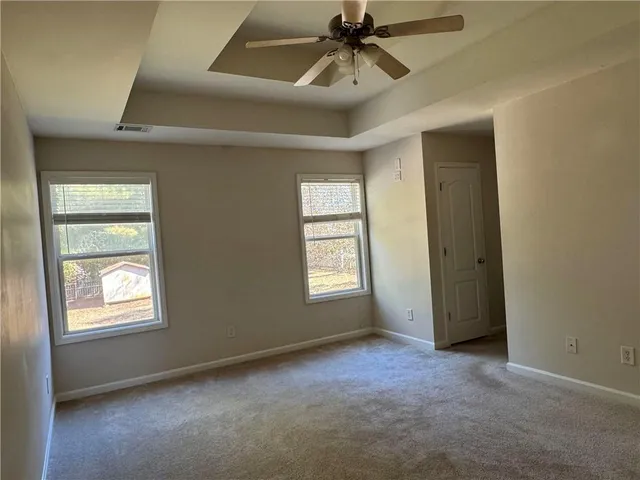 an empty room with windows and fan