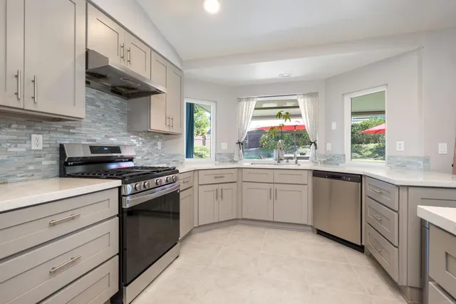 a kitchen with cabinets appliances a sink and a window